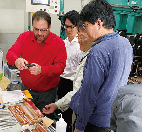 大阪大学の接合試験機の前で秋田大学宮野准教授（左から3人目）やNUMO技術部小川（左から2人目）から説明を受けるキーチ氏